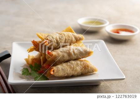 Deep Fried Crispy Wonton wrapped with shrimp and minced pork in white plate.Thai appetizer food with Sweet Chili Sauce and seafood sauce. 122763019
