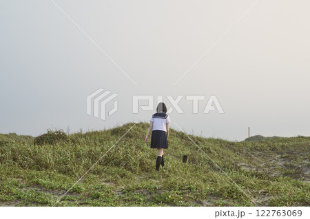 草原に立つ女子高校生の後ろ姿 122763069