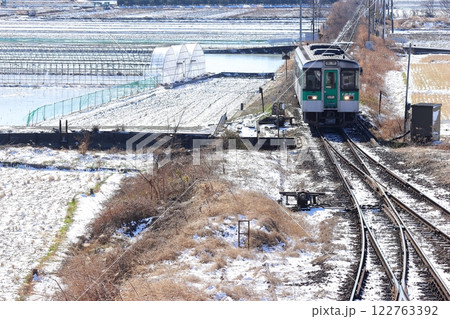 冬の朝、雪が少し積もった景色の中走る列車 122763392