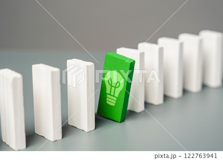 Domino with a green light bulb peeking out from a row. Concept of a good idea waiting for its time. Hidden opportunity, an innovative idea waiting for the right moment. Success, breakthrough solutions 122763941
