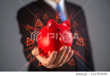 Businessman hands over a red piggy bank full of risks and dangers. Financial risks. Problematic loan portfolio. Economic uncertainty, high-risk savings, debt issues. Concept of financial caution Businessman hands over a red piggy bank full of risks and dangers. Financial risks. Problematic loan portfolio. Economic uncertainty, high-risk savings, debt issues. Concept of financial caution 122763949