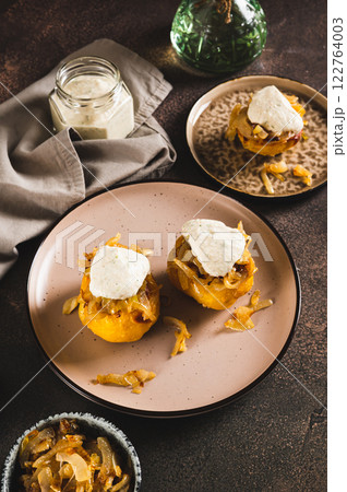 Baked potatoes with caramelized onions and hot sauce on a plate on the table vertical view Baked potatoes with caramelized onions and hot sauce on a plate on the table vertical view 122764003
