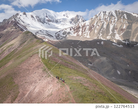 Aerial view on alpine landscape with hikers walking ridgeline up to snowy Pamir Mountains,Kyrgyzstan 122764513
