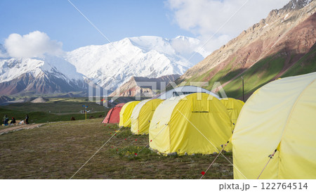 Expedition basecamp view with many tents build in valley under snowy Pamir Mountains, Kyrgyzstan Expedition basecamp view with many tents build in valley under snowy Pamir Mountains, Kyrgyzstan 122764514