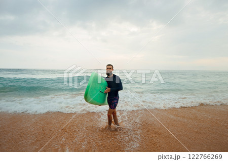 Young handsome male surfer with a surfboard on a sandy beach at ocean . Summer, vacation, sea 122766269