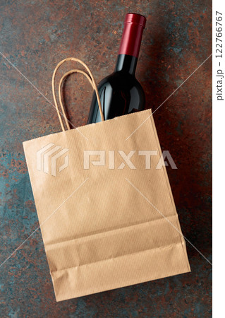 Bottle of red wine in a paper bag on a rusty background. Bottle of red wine in a paper bag on a rusty background. 122766767