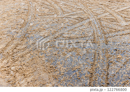Crossing tire tracks go over wet snowy road 122766800