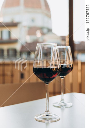 Tasting of local red wine on sunny summer balcony in Florence, Italy. Two glasses of red vine on the table. Cathedral Santa Maria del Fiore in Tuscany, Florence 122767522