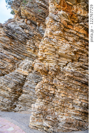 Layered rock texture in Budva, Montenegro. Sedimentary rocks with rugged surface of gray and brown. Natural formation of layers and cracks, geological structure. Layered rock texture in Budva, Montenegro. Sedimentary rocks with rugged surface of gray and brown. Natural formation of layers and cracks, geological structure. 122767729