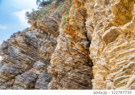 Layered rock texture in Budva, Montenegro. Sedimentary rocks with rugged surface of gray and brown. Natural formation of layers and cracks, geological structure. 122767730