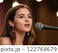 Young female singer performing on stage with microphone and spotlight Generated AI. 122768679