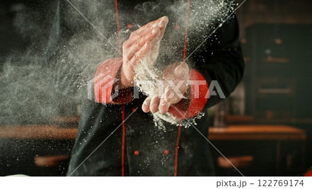 Freeze motion of baker clapping his hands with flour exploding. 122769174
