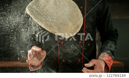 Freeze motion of baker processing yeast dough on pizza. Freeze motion of baker processing yeast dough on pizza. 122769184