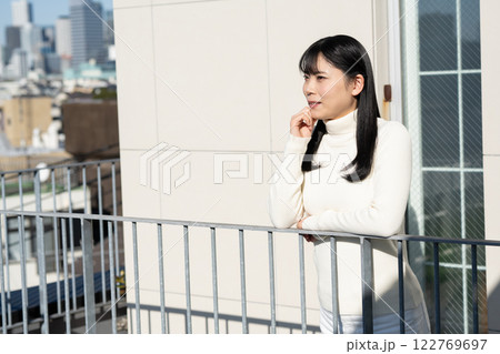 ベランダの手すりにもたれて立つ女性 ベランダの手すりにもたれて立つ女性 122769697
