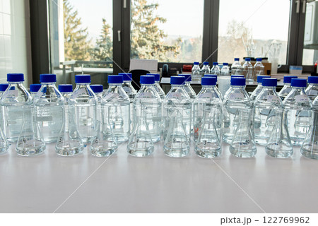 Laboratory equipment. Laboratory storage bottles with blue polypropylene cap on white table. 122769962
