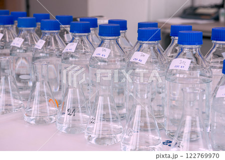 Laboratory equipment. Laboratory storage bottles with blue polypropylene cap on white table. 122769970