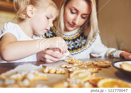 Confectionery workplace with women's hands decorating Christmas cookies. Home bakery, sunny sweet, winter holidays. Confectionery workplace with women's hands decorating Christmas cookies. Home bakery, sunny sweet, winter holidays. 122770047