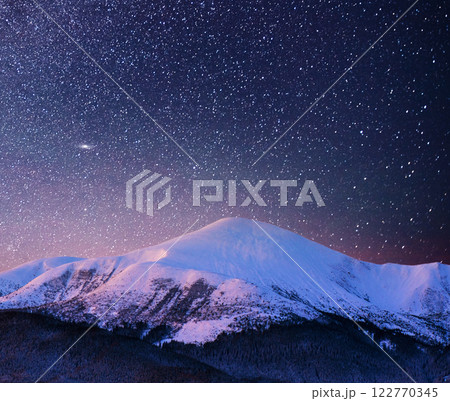 Beautiful winter landscape in the Carpathian mountains. Vibrant night sky with stars and nebula and galaxy. Deep sky astrophoto 122770345