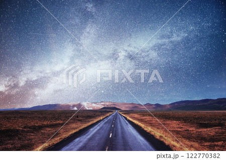 Starry Sky over the mountains. The asphalt road with white markings. Beautiful summer landscape. Soft filtering effect. Iceland Starry Sky over the mountains. The asphalt road with white markings. Beautiful summer landscape. Soft filtering effect. Iceland 122770382