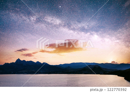 magnificent panorama of sunrise over the sea. Vibrant night sky with stars and nebula and galaxy. Deep sky astrophoto 122770392
