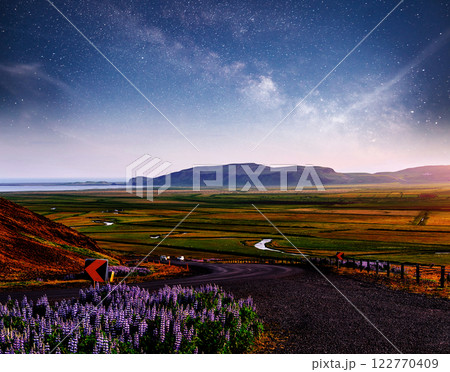 Starry Sky over the mountains. The asphalt road with white markings. Beautiful summer landscape. Soft filtering effect. Iceland 122770409