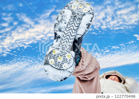 Snow boot sole with cleats, snowy tread pattern against . cloudy sky. Snow boot sole with cleats, snowy tread pattern against . cloudy sky. 122770496