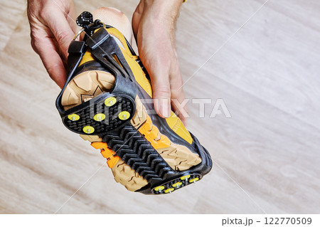 Anti-slip cleats with durable rubber straps and metal spikes provide secure traction for hiking boot on icy terrain. Anti-slip cleats with durable rubber straps and metal spikes provide secure traction for hiking boot on icy terrain. 122770509