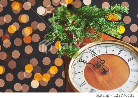 Happy New Year at midnight 2018, Old wooden clock with holiday lights and fir branches Happy New Year at midnight 2018, Old wooden clock with holiday lights and fir branches 122770533