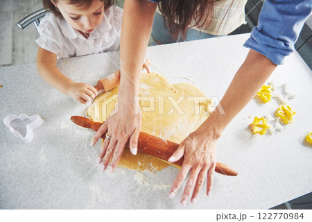 Happy family preparation holiday food concept. Family cooking Christmas cookies. Hands of mother and daughter preparing the dough on the table. Happy family in making cookies at home 122770984