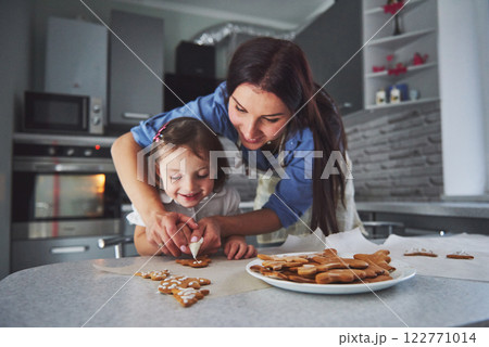 Happy family in the kitchen. Holiday food concept. Mother and daughter decorate cookies. Happy family in making homemade pastry. Homemade food and little helper 122771014