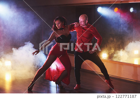 Skillful dancers performing in the dark room under the concert light and smoke. Sensual couple performing an artistic and emotional contemporary dance 122771187