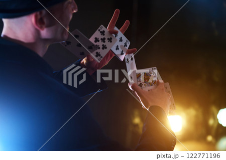 Magician showing trick with playing cards. Magic or dexterity, circus, gambling. Prestidigitator in dark room with fog Magician showing trick with playing cards. Magic or dexterity, circus, gambling. Prestidigitator in dark room with fog 122771196