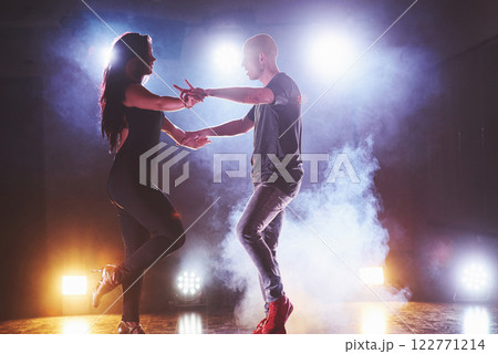 Skillful dancers performing in the dark room under the concert light and smoke. Sensual couple performing an artistic and emotional contemporary dance 122771214