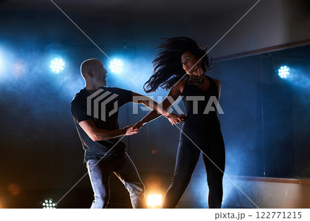Skillful dancers performing in the dark room under the concert light and smoke. Sensual couple performing an artistic and emotional contemporary dance 122771215