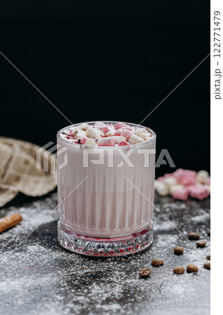 Cup of pink hot chocolate with marshmallows and powdered sugar on a rustic dark background 122771479