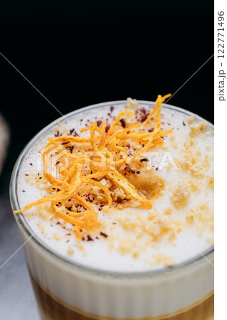 Gourmet layered latte with whipped foam, orange zest, and spices, served on a rustic dark surface Gourmet layered latte with whipped foam, orange zest, and spices, served on a rustic dark surface 122771496