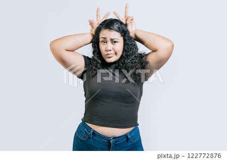 Funny girl making horns gesture with their fingers, gesture of betrayal. Funny young woman making horns gesture with fingers. Infidelity concept 122772876