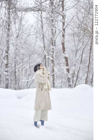 冬の雪国に佇むマフラーを巻いた日本人女性 122772904