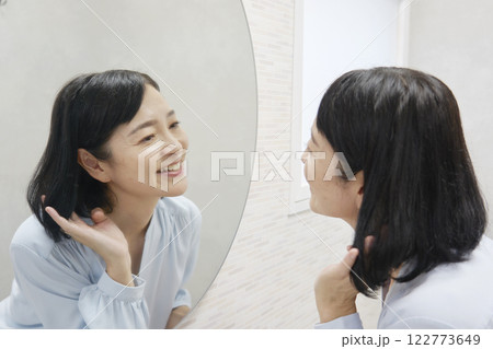 鏡を見てヘアセットする50代の女性 122773649