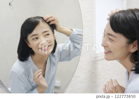 鏡を見てヘアセットする50代の女性 122773650