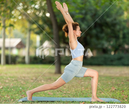 Adult woman doing yoga in warrior pose 122773820