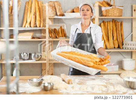 Female baker worker shows many products baguettes 122773901