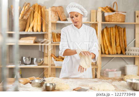 Professional female baker preparing pizza dough in bakery 122773949