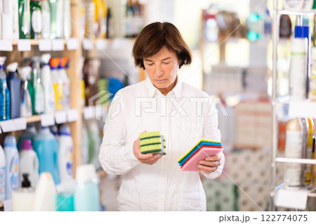 Elderly woman chooses sponges in store Elderly woman chooses sponges in store 122774075
