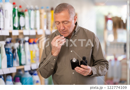 Elderly male shopper choosing scented cosmetics in supermarket 122774109