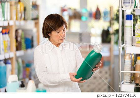 Elderly woman buyer chooses detergent in store Elderly woman buyer chooses detergent in store 122774110