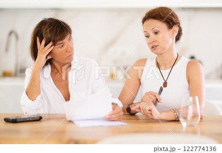 Two women discuss documents, try to solve financial problems 122774136