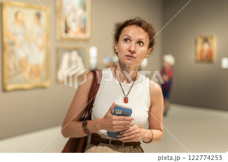 Woman with phone looking at art gallery 122774253