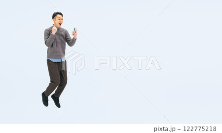 スマホを見ながらジャンプするカジュアルウェアのミドル男性の全身写真 スマホを見ながらジャンプするカジュアルウェアのミドル男性の全身写真 122775218