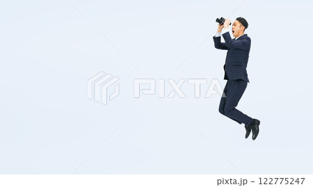 双眼鏡を持ってジャンプするミドル男性ビジネスパーソンの全身写真 双眼鏡を持ってジャンプするミドル男性ビジネスパーソンの全身写真 122775247